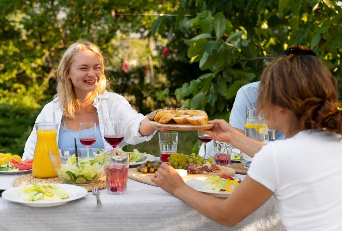 Finom ételekkel kínálják egymást a kerti parti vendégei.